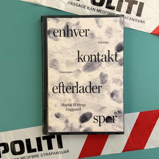 Foto af bogen "Enhver kontakt efterlader spor" af Martin Wittrup Enggaard. Bag bogen er der afspæringstape med teksten "Stop. Politi: Passage kan medføre strafansvar"